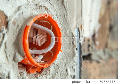 Socket orange boxes with wires in a wall. Cabling installation of electrical wires sticking out from electrical sockets hole on brick wall. Socket orange boxes with wires in a wall. Cabling installation of electrical wires sticking out from electrical sockets hole on brick wall. 79772117