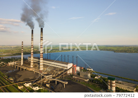 Aerial view of coal power plant high pipes with black smoke moving up polluting atmosphere. Aerial view of coal power plant high pipes with black smoke moving up polluting atmosphere. 79772412