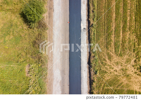 Aerial view of new road construction with newly layed black asphalt lane. 79772481