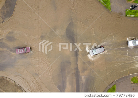 Aerial view of traffic cars driving on flooded road with rain water. Aerial view of traffic cars driving on flooded road with rain water. 79772486