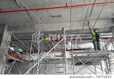 PUTRAJAYA, MALAYSIA -JANUARY 15, 2017: Construction workers wearing safety harness and adequate safety gear while working at high level at the construction site in Seremban, Malaysia. 79772653