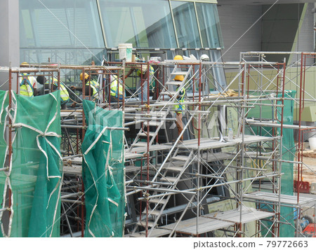 PUTRAJAYA, MALAYSIA -JANUARY 15, 2017: Construction workers wearing safety harness and adequate safety gear while working at high level at the construction site in Seremban, Malaysia. PUTRAJAYA, MALAYSIA -JANUARY 15, 2017: Construction workers wearing safety harness and adequate safety gear while working at high level at the construction site in Seremban, Malaysia. 79772663