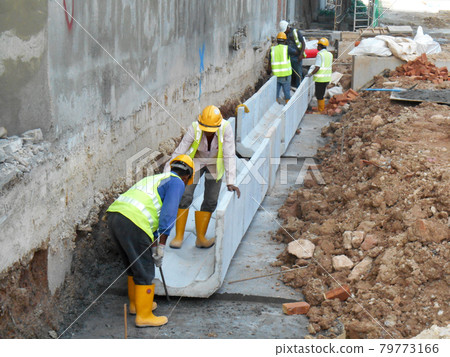 MALACCA, MALAYSIA -JANUARY 31, 2017: Drainage work by construction workers. Construction workers installing precast u-shape concrete drain at the construction site.  79773166