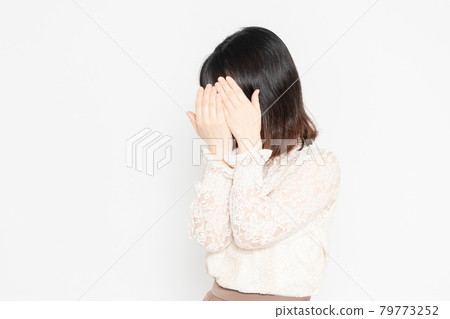 Young woman in lace blouse standing in front of white background, hiding her face 79773252