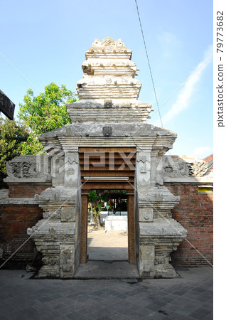 JOGJAKARTA, INDONESIA -JUNE 12, 2014: Entrance arch at old Masjid Besar Mataram Kotagede, Jogjakarta Indonesia. The arch was made from brick and hand made carving stone in traditional Balinese Style JOGJAKARTA, INDONESIA -JUNE 12, 2014: Entrance arch at old Masjid Besar Mataram Kotagede, Jogjakarta Indonesia. The arch was made from brick and hand made carving stone in traditional Balinese Style 79773682