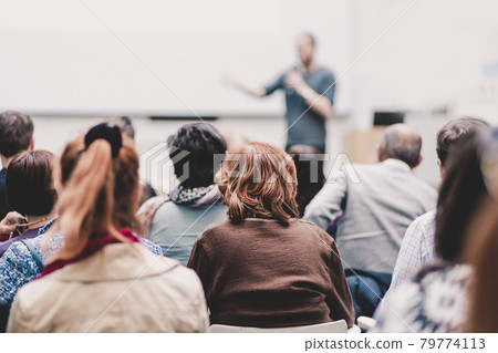 Man giving presentation in lecture hall at university. Man giving presentation in lecture hall at university. 79774113