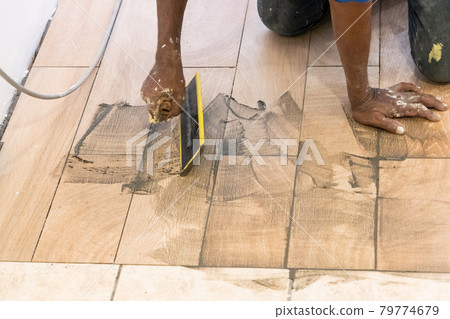 Worker applying grout onto newly laid ceramic tile. Motion blur intended. Worker applying grout onto newly laid ceramic tile. Motion blur intended. 79774679