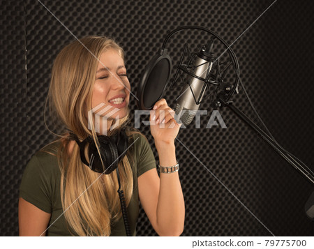 Young beautiful female musician with guitar is testing the sound system in the recording studio before taking part in the recording. 79775700
