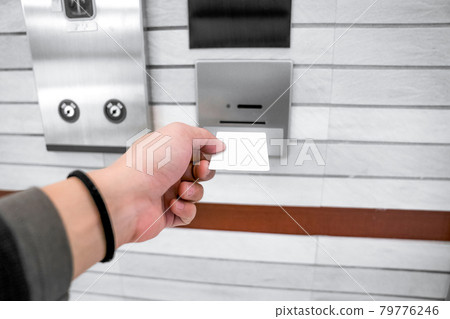 securing lift or elevator access control, man's hand is holding a key card lay up to insert in card hold for unlocking elevator doors before up or down. securing lift or elevator access control, man's hand is holding a key card lay up to insert in card hold for unlocking elevator doors before up or down. 79776246