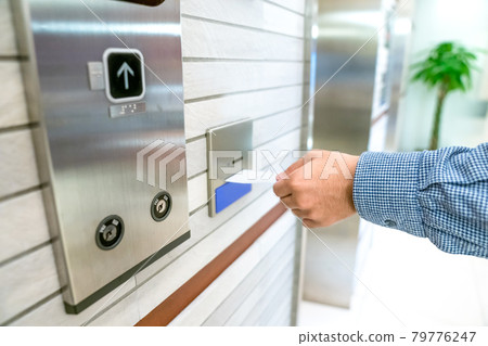 securing lift or elevator access control, man's hand is holding a key card lay up to insert in card hold for unlocking elevator doors before up or down. securing lift or elevator access control, man's hand is holding a key card lay up to insert in card hold for unlocking elevator doors before up or down. 79776247