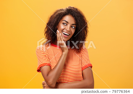 Cute creative and feminine stylish african american young female in striped t-shirt leaning head on palm gazing left with curious and adorable expression delightfully listening interesting story Cute creative and feminine stylish african american young female in striped t-shirt leaning head on palm gazing left with curious and adorable expression delightfully listening interesting story 79776364