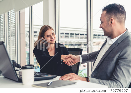 Businessman handshake businesswoman in office. Businessman handshake businesswoman in office. 79776907