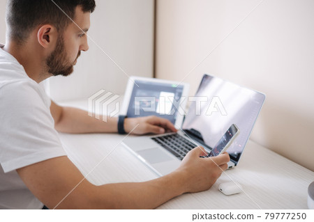 Man looking at finance chart on laptop and tablet, day trader, investing from home. Young man monitors his investments. Ambitious businessman 79777250
