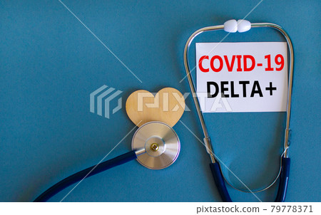 New Covid-19 delta plus variant strain symbol. White card, words Covid-19 delta plus and stethoscope, blue background. Wooden heart. Medical and covid-19 delta plus variant strain concept, copy space. 79778371