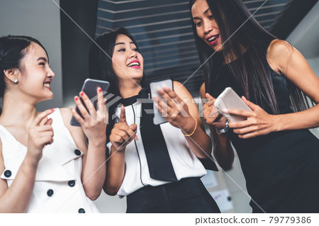 Three women friends chat with mobile phone device. 79779386