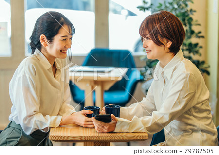 Women talking while looking at their smartphones Women talking while looking at their smartphones 79782505