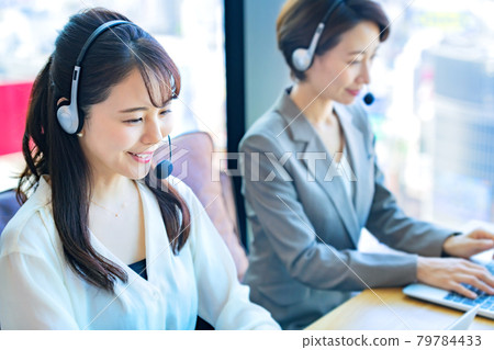 A young female operator wearing a headset in the office A young female operator wearing a headset in the office 79784433