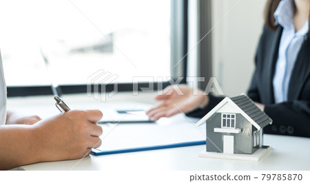 A real estate agent with a home model is talking to clients about renting a house and buying home insurance and contracting the contract after the formal negotiation is completed 79785870