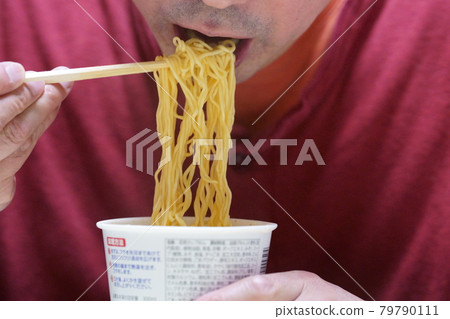 Men eating cup noodles with their mouths up 79790111