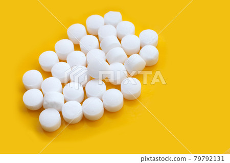 Naphthalene mothballs on yellow backgrond. 79792131