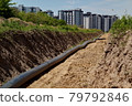 A large pipe lies in the trench. Water routing to the new house. house with water. residential complex 79792846