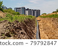 A large pipe lies in the trench. Water routing to the new house. house with water. residential complex 79792847