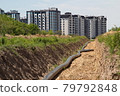 A large pipe lies in the trench. Water routing to the new house. house with water. residential complex 79792848
