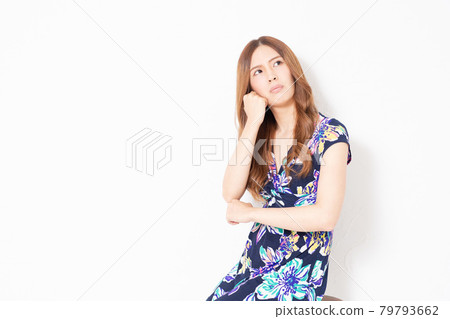 A young woman in a blue one-piece, thinking in front of a white wall A young woman in a blue one-piece, thinking in front of a white wall 79793662