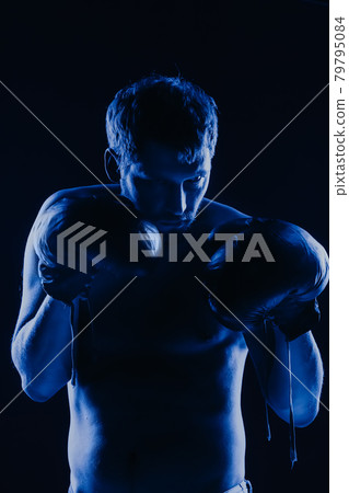 Mixed martial arts fighter in gloves in neon blue. Male portrait of a boxer 79795084