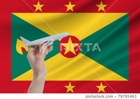 Airplane in hand with national flag of Grenada. Travel to Grenada Airplane in hand with national flag of Grenada. Travel to Grenada 79795463