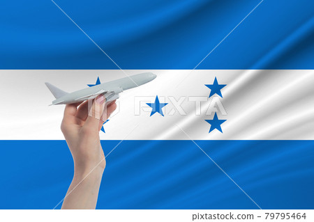 Airplane in hand with national flag of Honduras. Travel to Honduras Airplane in hand with national flag of Honduras. Travel to Honduras 79795464