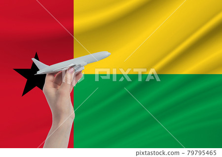 Airplane in hand with national flag of Guinea-Bissau. Travel to Guinea-Bissau Airplane in hand with national flag of Guinea-Bissau. Travel to Guinea-Bissau 79795465
