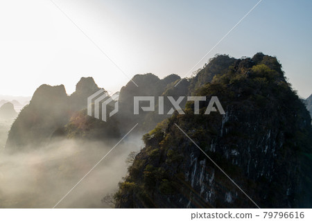 Aerial of beautiful sunrise over foggy karst mountain peak landscape Aerial of beautiful sunrise over foggy karst mountain peak landscape 79796616