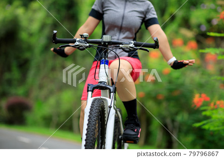Woman no handed cycling on tropical park trail in summer Woman no handed cycling on tropical park trail in summer 79796867