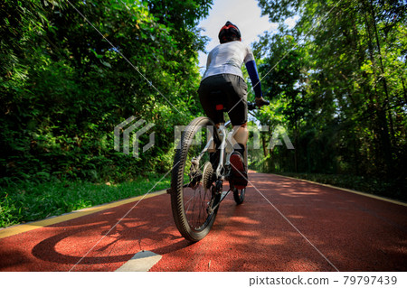 Woman cycling on bike path at sunrise park 79797439