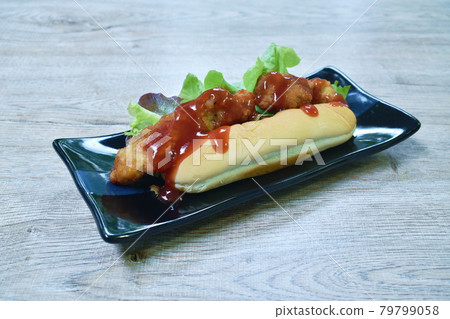 hot dog stuffed fried chicken with lettuce dressing ketchup on dish 79799058