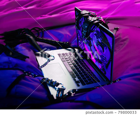 A set of BDSM toys for sex on a laptop on a bright neon background 79800033