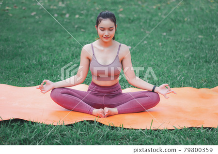 Asian woman practicing yoga in Root Bond, Mula Bandha pose on the mat in outdoor park. Asian woman practicing yoga in Root Bond, Mula Bandha pose on the mat in outdoor park. 79800359