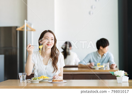 A woman eating pasta at a cafe 79801017