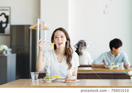 A woman eating pasta at a cafe 79801018