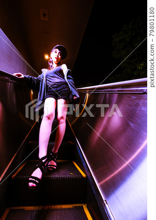 A beautiful woman on an escalator that looks like a different space that is stopped A beautiful woman on an escalator that looks like a different space that is stopped 79801180