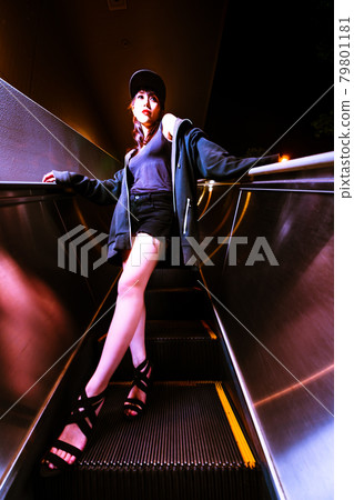 A beautiful woman on an escalator that looks like a different space that is stopped 79801181