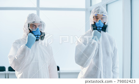 colleagues in biohazard suits standing in the lab. colleagues in biohazard suits standing in the lab. 79802423