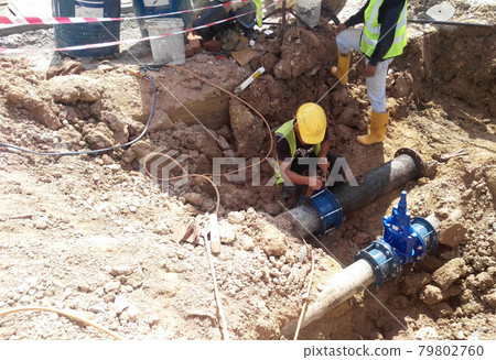 SEREMBAN, MALAYSIA -MAY 15, 2017: Construction workers fixing underground pipes at the construction site. Minor excavation works involved. SEREMBAN, MALAYSIA -MAY 15, 2017: Construction workers fixing underground pipes at the construction site. Minor excavation works involved. 79802760