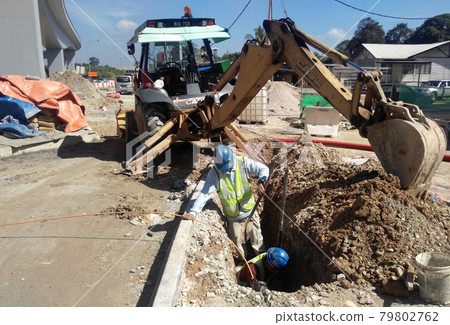 SEREMBAN, MALAYSIA -MAY 15, 2017: Construction workers fixing underground pipes at the construction site. Minor excavation works involved. SEREMBAN, MALAYSIA -MAY 15, 2017: Construction workers fixing underground pipes at the construction site. Minor excavation works involved. 79802762