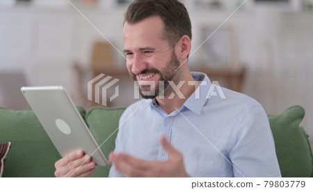 Young Man Celebrating Success on Tablet Young Man Celebrating Success on Tablet 79803779