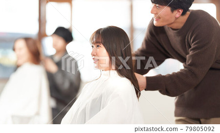 Female customer having a hair stylist cut her hair 79805092