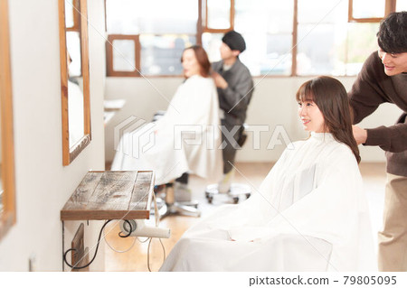 Female customer having a hair stylist cut her hair 79805095
