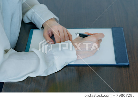 一個年輕女子的手在剪貼板上寫下附件 79807293