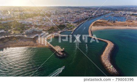 Aerial view from the sky of the Portuguese coastline of the Algarve zone of Lagos city. Boats and ships are moving in the direction of the port. 79808396